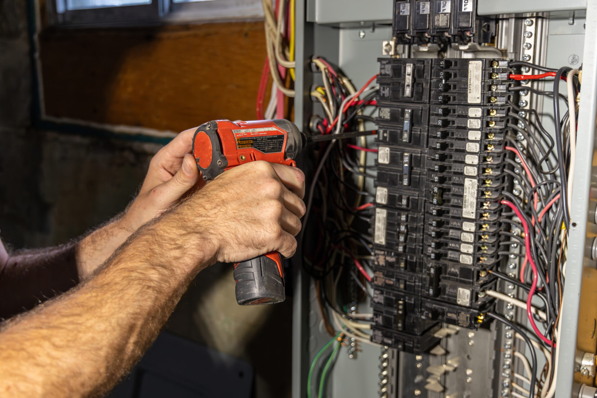 Electrician installing a ground wire in a breaker box Electrician installing a ground wire in a breaker box