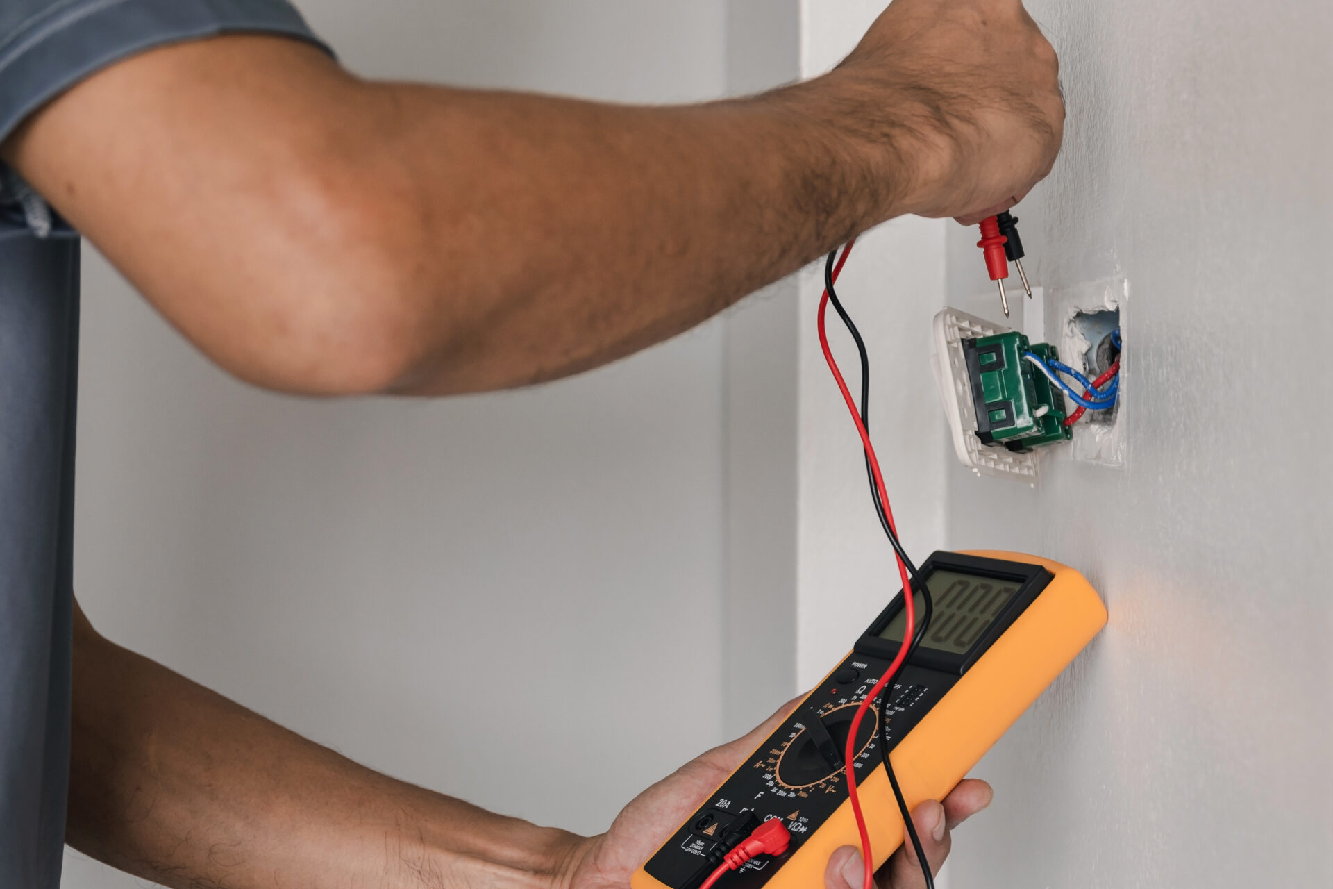 Electrician is using a digital meter to measure the voltage at the power outlet in on the wall. Electrician is using a digital meter to measure the voltage at the power outlet in on the wall.