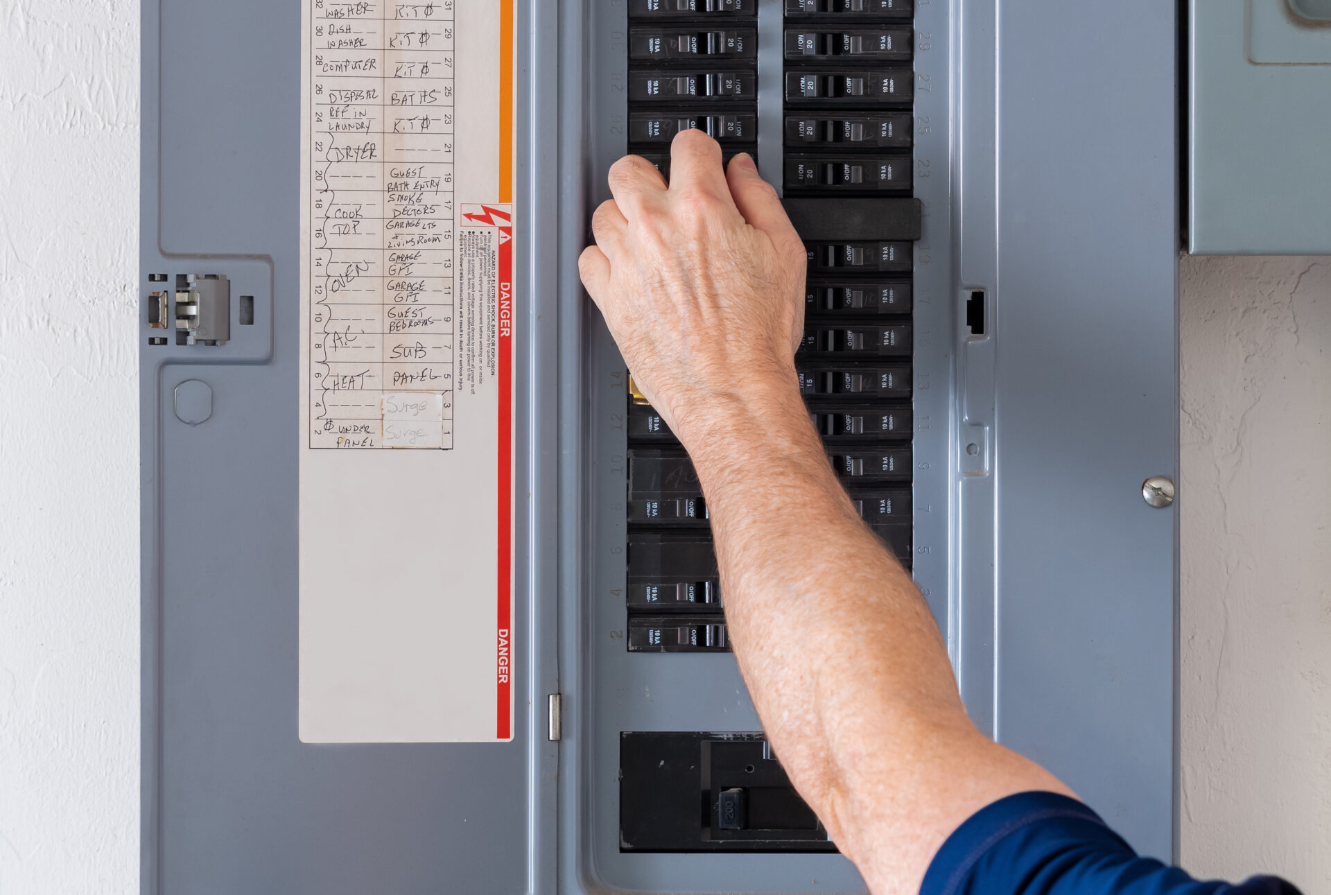 Resetting tripped breaker in residential electricity power panel. Electrician turning off power for electrical outlet at circuit breaker box. Resetting tripped breaker in power panel
