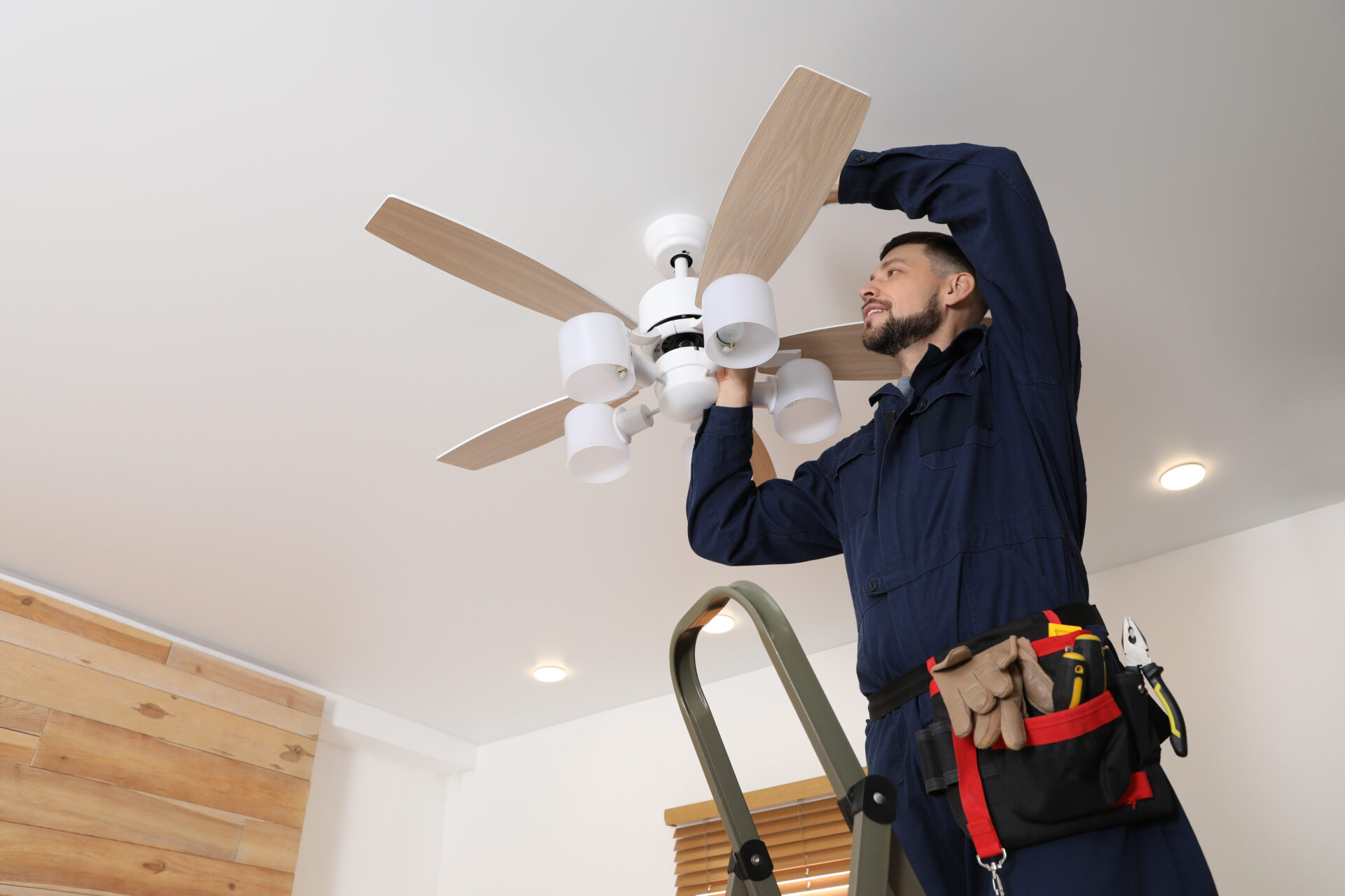 Electrician repairing ceiling fan with lamps indoors. Space for Electrician repairing ceiling fan with lamps indoors.