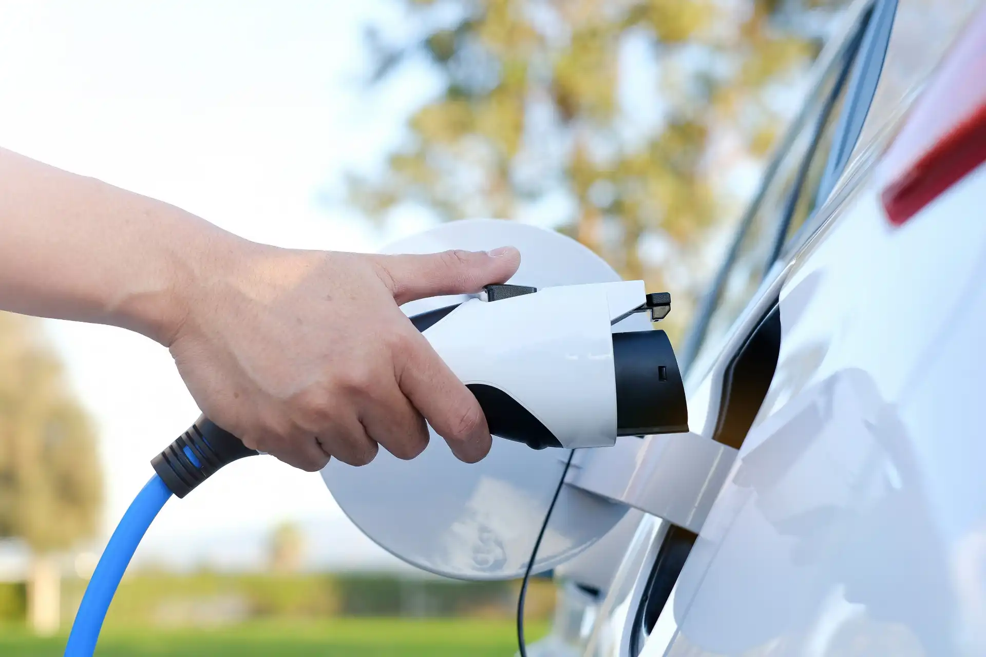 Adobe-Express-file1 Woman connecting an EV charger to a vehicle